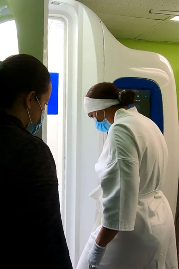Doctora ayudando al cliente a usar la máquina de crioterapia de cuerpo entero en EasyCare Tampa